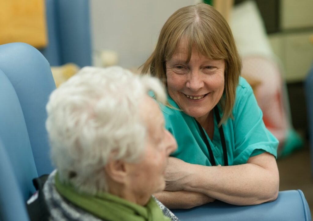 Care worker in green uniform supporting an older adult at home